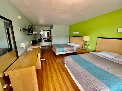 Cette chambre d'hôtel dispose de 2 lits et de murs verts. dans l'établissement Country Yard Inn and Suites, à Sikeston