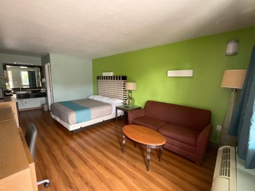 a room with a bed and a couch and a table at Country Yard Inn and Suites in Sikeston
