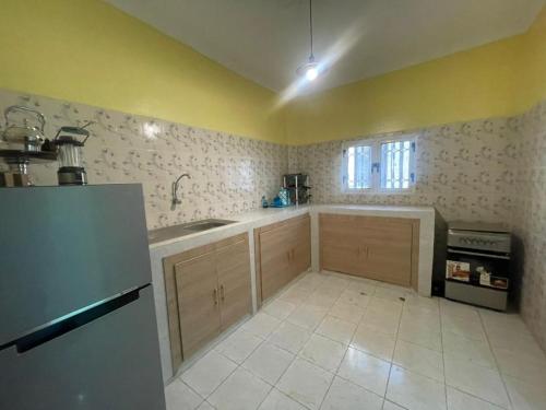 a kitchen with wooden cabinets and a white tile floor at Ace Appartement Meublé in Nouakchott