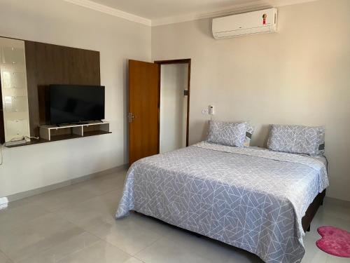a bedroom with a bed and a flat screen tv at Apartamento Sorriso in Sorriso