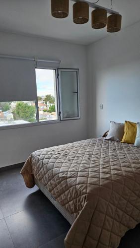 a bedroom with a large bed and a window at Departamento Villarino in Puerto Madryn