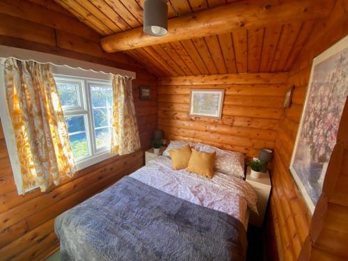 een slaapkamer met een bed in een blokhut bij Cosy Log Cabin Snowdonia Eryri in Trawsfynydd