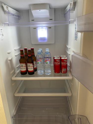 a refrigerator filled with bottles of soda and water at Apartamento Sorriso in Sorriso