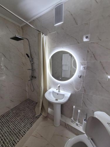 Baño blanco con lavabo y espejo en Апартаменты посуточно, en Temirtaū