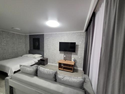 um quarto de hotel com uma cama, um sofá e uma televisão em Апартаменты посуточно em Temirtaū