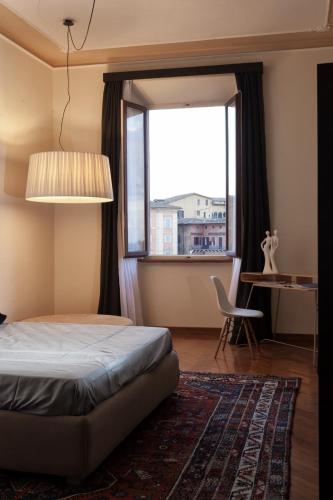a bedroom with a bed and a window and a chair at Palazzo Giorgi in Siena