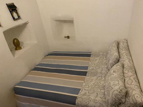 a small bedroom with a bed with a striped mattress at Dar Tetuania in Tétouan