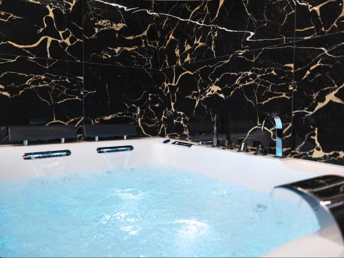 La salle de bains est pourvue d'une baignoire et d'un mur en marbre noir. dans l'établissement Vegas Room - Luxury, à Serémange-Erzange