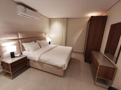 een slaapkamer met een groot bed en een nachtkastje bij شقة فاخرة بالقرب من البوليفارد دخول ذاتي a14 in Riyad