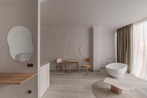 a white bathroom with a tub and a table at Sfumato Rooms in Odesa