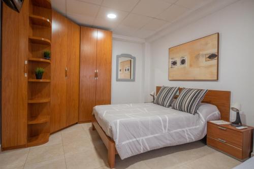 - une chambre avec un lit et une armoire en bois dans l'établissement THE PHOTOGRAFIC FLAT, à Malaga