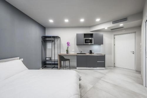 a white bedroom with a bed and a kitchen at Borgo degli Ulivi in Formigine