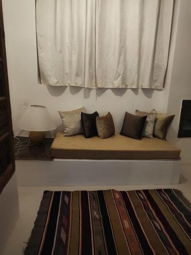 a bench with many pillows sitting under a window at Hôte sahara & spa TADIGHOUST in El Hara