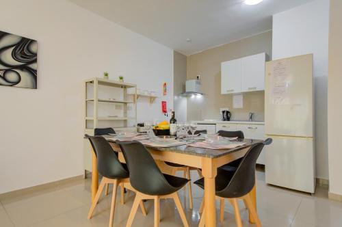 a kitchen with a wooden table with chairs and a refrigerator at CityScape Gzira Holiday Apartments and Penthouse in Il-Gżira