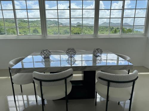 a dining room with a glass table and chairs at NEW Luxury VILLA CapEstate Saint Lucia Ocean View in Cap Estate