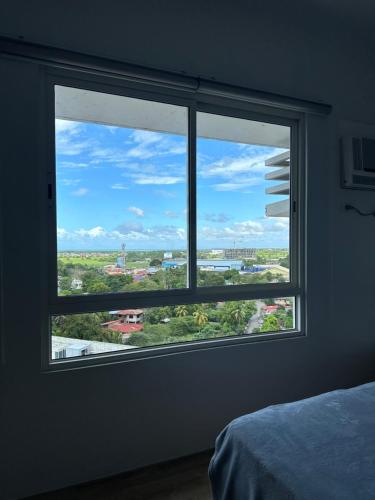 a window in a bedroom with a view of a city at Cozy Condo bedroom in Bacolod City in Bacolod