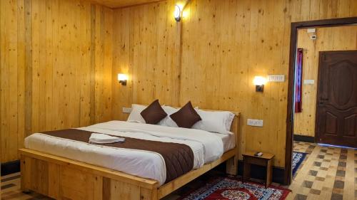 1 dormitorio con 1 cama grande en una habitación con paredes de madera en Loft wood house en Kodaikānāl