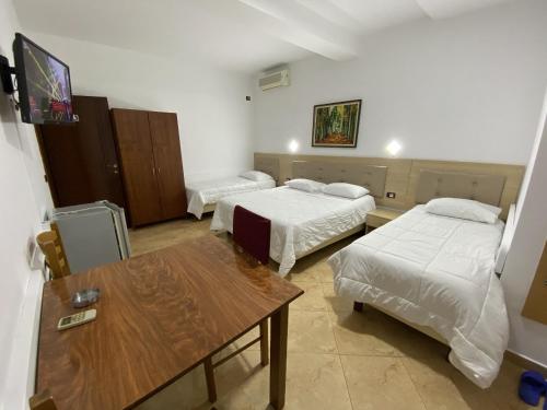 a room with two beds and a table and a tv at Hotel Martini in Vlorë