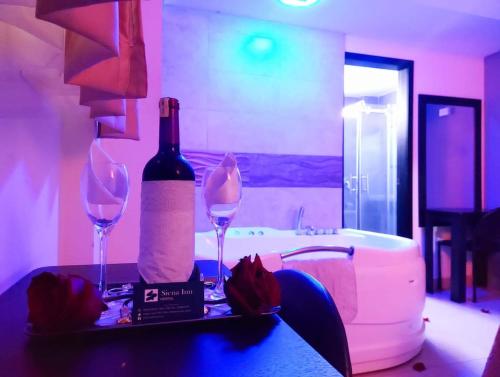 Una botella de vino y dos copas en una mesa. en SIENA Inn HOSTAL, en Quito
