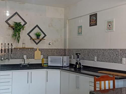 a kitchen with white cabinets and a black counter top at Residencial Vista Bela in Bombinhas