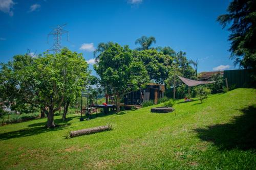 a grassy yard with trees and a building at T24 Tinyhouse Container in Ibiúna