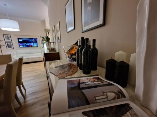 Guest House Canalis 17 في أوريستانو: غرفة معيشة مع طاولة مع زجاجات النبيذ عليها