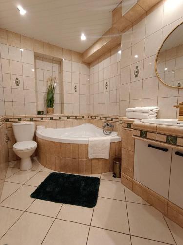 a bathroom with a tub and a toilet and a sink at Apartament Wileńska 15 in Sejny