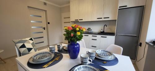 una cocina con una mesa con platos y un jarrón de flores en Apartament Wileńska 15, en Sejny