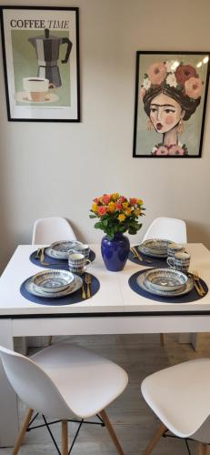 a table with plates and a vase of flowers on it at Apartament Wileńska 15 in Sejny