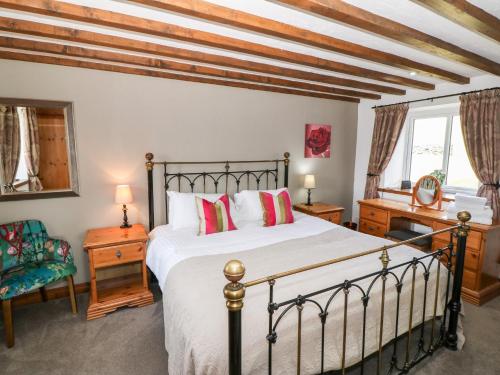 a bedroom with a bed and a desk and a window at Orsedd Wen Cottage in Betws-y-coed