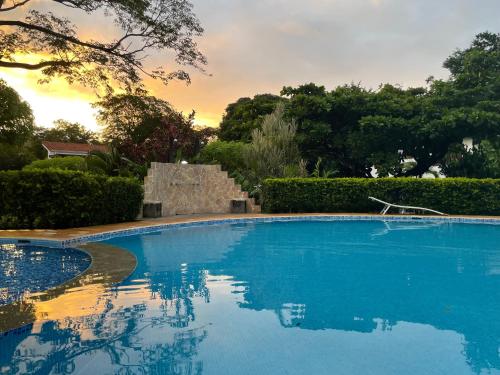 une piscine bleue avec un coucher de soleil en arrière-plan dans l'établissement Villa Hermosa, à Playa Hermosa