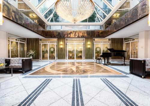 a lobby with a grand piano and a grand chandelier at Best Western Premier Grand Hotel Russischer Hof in Weimar