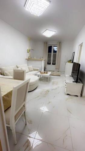 a white living room with white furniture and a tv at Golden House in Dreux