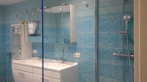 a blue tiled bathroom with a sink and a shower at Unseburger Brauhaus GmbH Ferienwohnung 5 in Unseburg