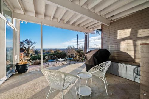 a patio with white chairs and a table and a large window at Lunceford - Northglenn in Northglenn