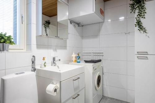 a white bathroom with a sink and a washing machine at City Island Studio Apartment, 4 beds, free street parking with parking disc, bus stop 200m in Helsinki