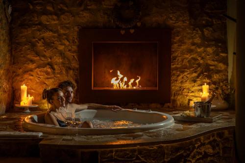 a woman sitting in a bath tub in front of a fireplace at PALAZZO DEL CAPITANO Wellness & Relais - Luxury Borgo Capitano Collection in San Quirico dʼOrcia