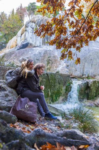 a man and woman sitting on a rock near a waterfall at PALAZZO DEL CAPITANO Wellness & Relais - Luxury Borgo Capitano Collection in San Quirico dʼOrcia