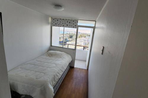 Habitación pequeña con cama y ventana en Amplio Departamento Central Piso 11 Frente Casino Luckia, en Arica