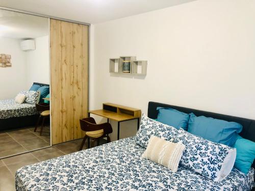 Un dormitorio con una cama con almohadas azules y una mesa. en Appartement neuf 4/6 personnes, près de la plage en Les Trois-Îlets