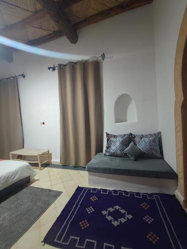a bedroom with a bed and a blue rug at Hôte sahara & spa TADIGHOUST in El Hara