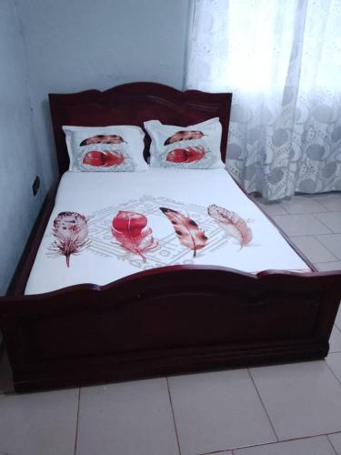 a bed with red roses on a white blanket at RESIDENCE DU PELERIN - Villa l'écrin de verdure à Bandjoun in Bandjoun