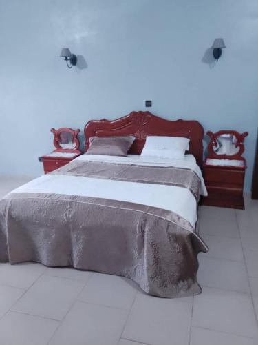 a bedroom with a large bed with a wooden headboard at RESIDENCE DU PELERIN - Villa l'écrin de verdure à Bandjoun in Bandjoun