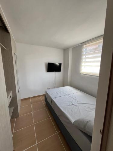 Habitación blanca con cama y TV en Laurel de Florida Apto, en Medellín