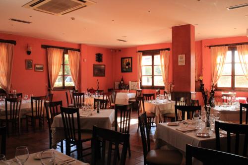 comedor con mesas, sillas y paredes rojas en Hotel Rural Carlos I, en Garganta la Olla