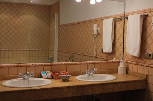 uma casa de banho com 2 lavatórios e um espelho grande em Hotel Rural Carlos I em Garganta la Olla