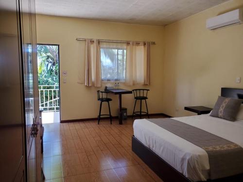 1 dormitorio con cama, mesa y balcón en Garita Inn Delux, en La Garita