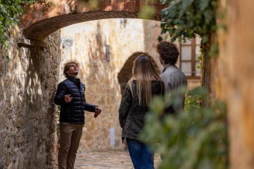 a group of three people walking down an alley at PALAZZO DEL CAPITANO Wellness & Relais - Luxury Borgo Capitano Collection in San Quirico dʼOrcia