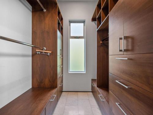 a walk in closet with wooden cabinets and a window at Luxury Coastal Home - Pool, Spa, AC, & Ocean Views in Solana Beach