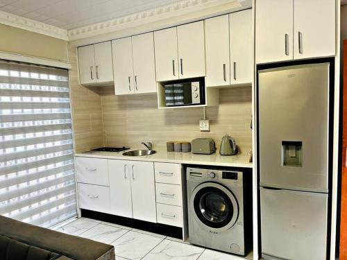a kitchen with white cabinets and a washer and dryer at Luxury Garden Cottage in Welkom in Welkom